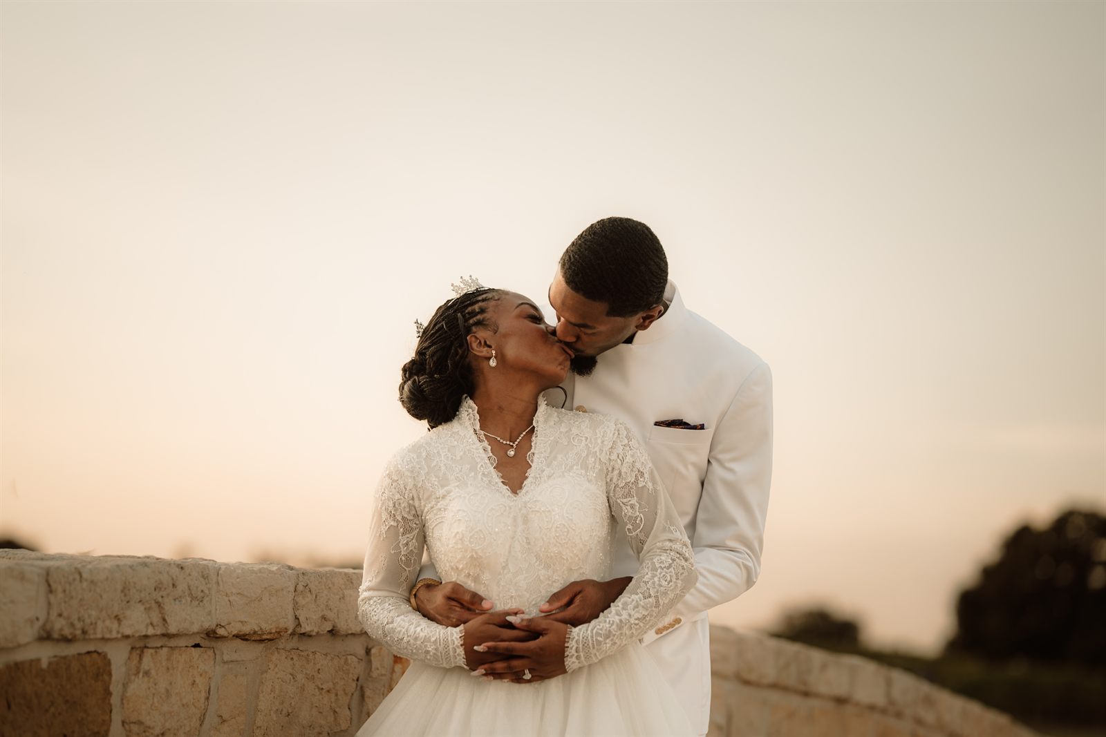 Newlyweds kissing on a stone bridge at dusk