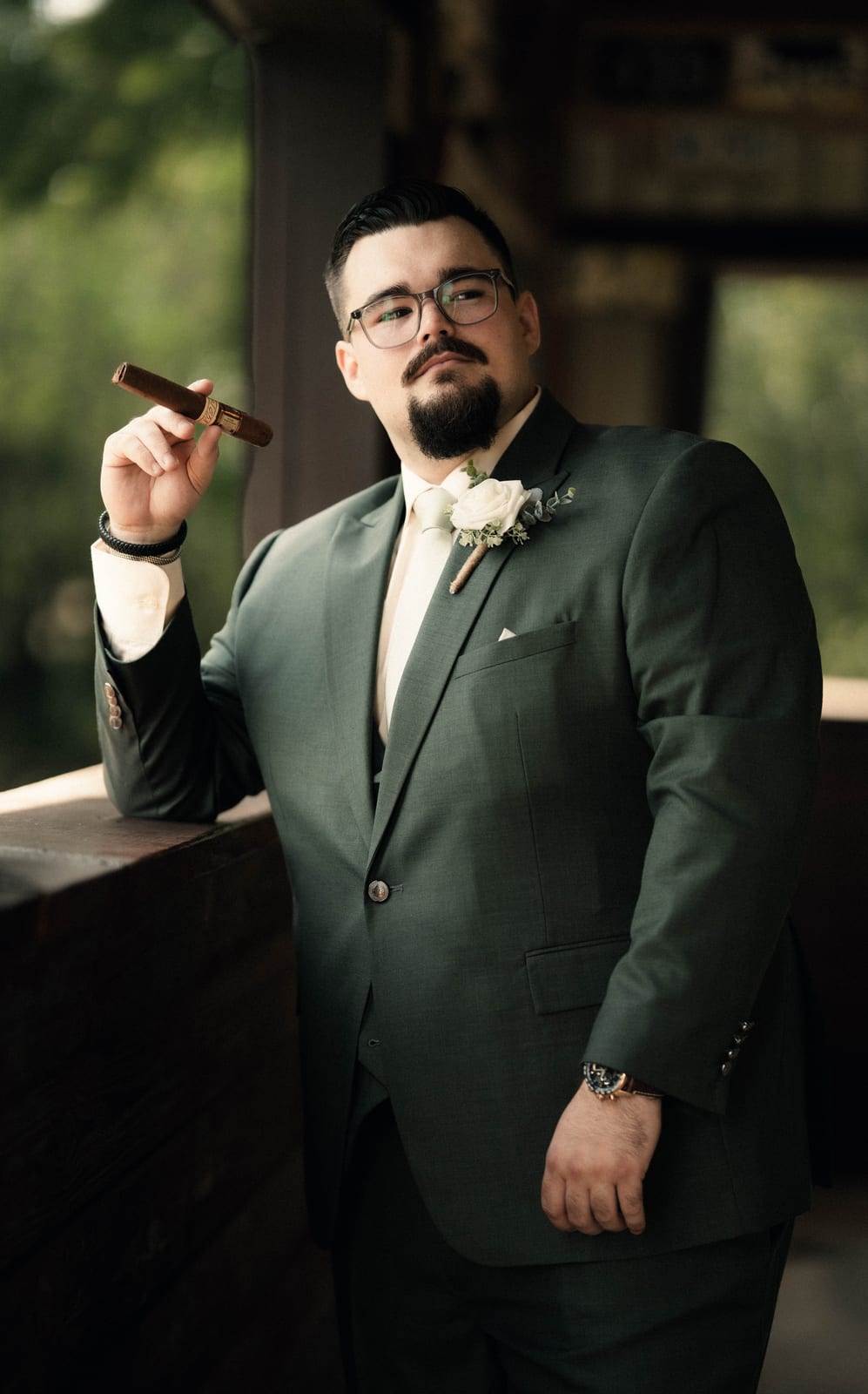 Groom in a dark green suit holding a cigar