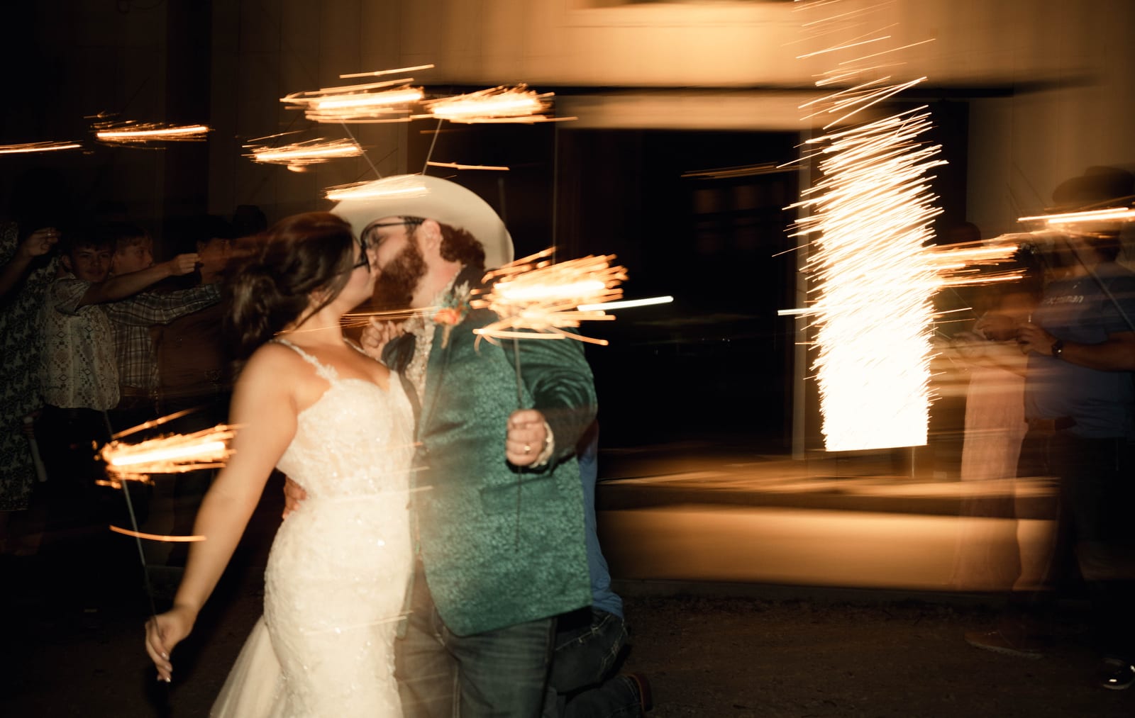 Bride and groom in a cowboy hat dancing through trails of sparkler light